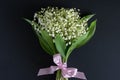 Happy holiday concept. A bouquet of beautiful fragrant white lilies of the valley on a dark background Royalty Free Stock Photo