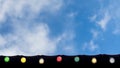 Happy holiday, event celebration background concept: line of colorful light bulbs on the roof eaves looking up, blue sky and white Royalty Free Stock Photo