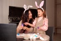 Happy holiday! mummy with child painting eggs. Family preparing for Easter. Cute girls wearing bunny ears