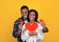 Happy holiday, romance, anniversary and love. Happy african american guy and lady holding red hearts