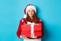 Happy holidays and Christmas concept. Cute redhead girl holding presents and pucker lips for kiss, wearing santa hat and Royalty Free Stock Photo