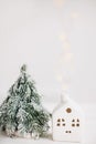 Happy holidays. Christmas little house  with golden lights bokeh and tree on white background. Festive modern decor.  Miniature Royalty Free Stock Photo