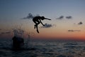 Happy holidays concept. Young kid jumping in the sea under sunset sky with sun and cloud. Happy family on ocean beach Royalty Free Stock Photo
