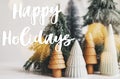 Happy holidays Greeting card. Happy holidays text handwritten on little christmas trees in festive lights, miniature winter forest Royalty Free Stock Photo