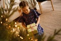 Happy holidays. Little child opening present near Christmas tree. The girl laughing and enjoying the gift. Royalty Free Stock Photo