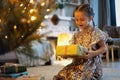 Happy holidays. Little child opening present near Christmas tree. The girl laughing and enjoying the gift. Royalty Free Stock Photo