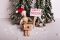 Happy Holidays picket sign held by wooden jointed manikin doll with wrapped gift wearing a Santa Claus hat wintery scene Royalty Free Stock Photo