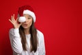 Happy Holidays. Playful Young Lady Wearing Santa Hat Covering Eye With Pompom Royalty Free Stock Photo