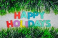 Happy Holidays text on glitter ornated with green tinsel garlands.