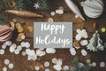 Happy Holidays text on greeting card, christmas ornaments, decorations, confetti, branches on rustic wood flat lay. Season`s Royalty Free Stock Photo