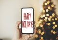 Happy Holidays text on phone screen on background of golden beau Royalty Free Stock Photo