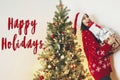 happy holidays text, seasons greetings, merry christmas and happy new year concept. happy stylish woman in santa hat holding many Royalty Free Stock Photo