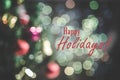 Happy holidays text sign on a blurred background of Christmas trees and ornaments and bokeh Royalty Free Stock Photo