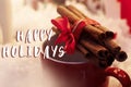 Happy holidays text sign on cinnamon sticks with ribbon on red c