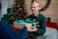 Happy holidays. Young cheerful couple in love with a gift for Christmas. Husband gives his wife a gift Royalty Free Stock Photo