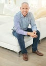 Happy at home. Portrait of a smiling mature man sitting on a sofa in his living room. Royalty Free Stock Photo