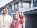 Happy homeowners Asian muslim couple pointing their new house