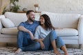 Happy homeowners millennial spouses resting in cozy living room