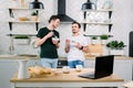 Happy homosexual boys talking each other and having breakfast. Everyday morning routine of gay couple life in kitchen at Royalty Free Stock Photo