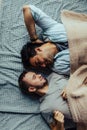 Handsome sleepy man with bristle kissing good night male partner lying in bed Royalty Free Stock Photo