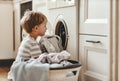 Happy householder child boy in laundry with washing machine