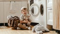 Happy householder child boy in laundry with washing machine