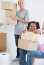 Happy housemates carrying cardboard moving boxes