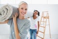 Happy housemates carrying rolled up rug in new home Royalty Free Stock Photo