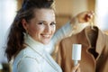 Happy housewife cleaning coat on hanger with lint roller