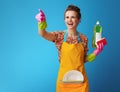 Happy housewife with sponge and dishwashing liquid on blue