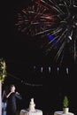 Happy hugging bride and groom watching beautiful colorful fireworks in the night sky. wedding day, party