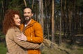 Happy husband and wife hugging in pine forest