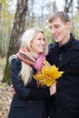 Happy husband and wife with yellow maple leafle look at other