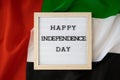 HAPPY INDEPENDENCE DAY text frame on United Arab Emirates waving flag made from silk material. Commemoration Day Muslim Royalty Free Stock Photo