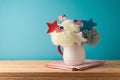 Happy Independence Day, 4th of July celebration concept with flowers decoration and USA flags on wooden table over blue background Royalty Free Stock Photo