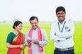 Happy Indian banker standing with crossed arms by looking camera in front of village couple counting money at farmland -