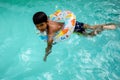 Happy Indian boy swimming in a pool, Kid wearing swimming costume along with air tube during hot summer vacations, Children boy in