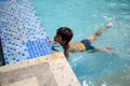 Happy Indian boy swimming in a pool, Kid wearing swimming costume along with air tube during hot summer vacations, Children boy in Royalty Free Stock Photo