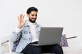 Happy indian business man in casual making video call from home couch, looking at camera, smiling, waving hand hello, attending Royalty Free Stock Photo