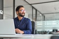 Happy Indian business man ceo executive looking away working on laptop. Royalty Free Stock Photo