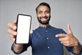 Happy indian business man pointing at mobile phone screen mockup. Royalty Free Stock Photo