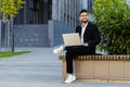 Happy Indian businessman typing working remote on wireless laptop computer browsing online outdoors Royalty Free Stock Photo