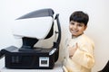 Happy Indian child boy examining eyesight modern ophthalmology equipment in clinic. Patient kid male scan checkup iris examines Royalty Free Stock Photo