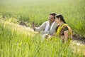 Happy Indian couple farmers examining crop in agricultural field