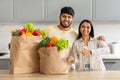 Happy Indian Couple With Grocery Bags Standing In Kitchen Interior Royalty Free Stock Photo