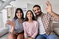 Happy indian couple and teen child daughter waving hands looking at camera.