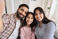 Happy indian couple and teen daughter taking selfie looking at phone camera. Royalty Free Stock Photo