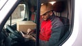 Happy indian courier using tablet in the van