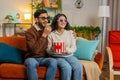 Happy Indian family couple in 3D glasses eating popcorn and watching comedy movie sitting on sofa Royalty Free Stock Photo