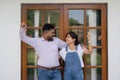 Happy Indian family couple showing new house key to camera while in front of the door. Success in moving house